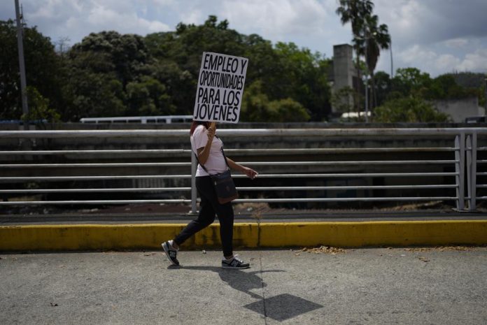 Una mujer lleva un cartel que pide oportunidades laborales en una marcha por el Día Internacional de la Mujer en Caracas, Venezuela, el miércoles 8 de marzo de 2023. (AP Foto/Ariana Cubillos)