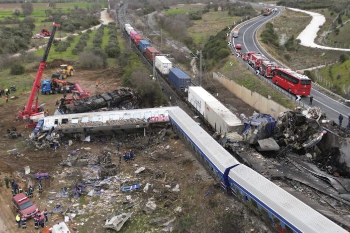 Una grúa, bomberos y rescatistas trabajan una colisión en Tempe cerca cerca de la ciudad de Larissa, Grecia, el miércoles 1 de marzo de 2023. Había docenas de muertos y heridos después de que un tren con cientos de pasajeros chocara con un tren de mercancías en el norte de Grecia. (AP Foto/Vaggelis Kousioras)