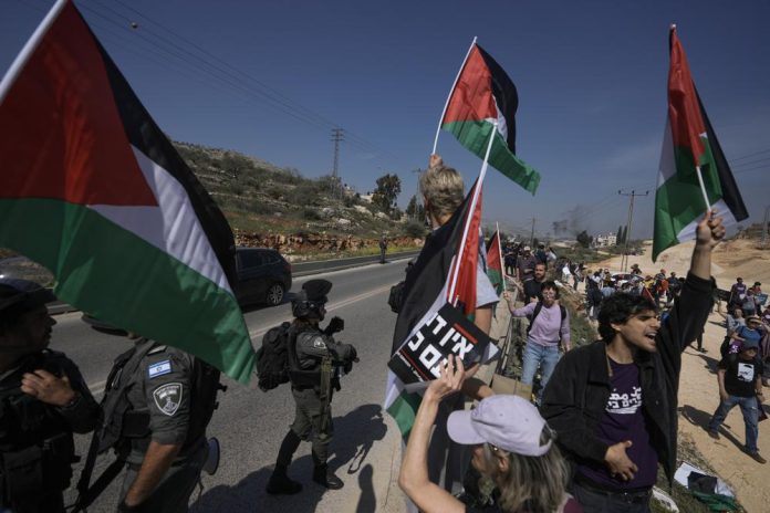 Agentes de la policía de frontera israelí impiden que cientos de activistas de izquierda israelíes realicen un acto solidario en una población palestina que colonos judíos extremistas incendiaron días atrás, cerca de Hawara, Cisjordania, viernes 3 de marzo de 2022. (AP Foto/Majdi Mohammed)