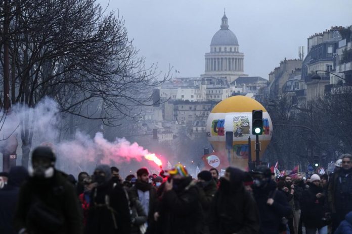 Manifestantes marchan, con el Panteón al fondo, durante una protesta contra la reforma de las pensiones, el 7 de marzo de 2023 en París. (AP Foto/Lewis Joly)