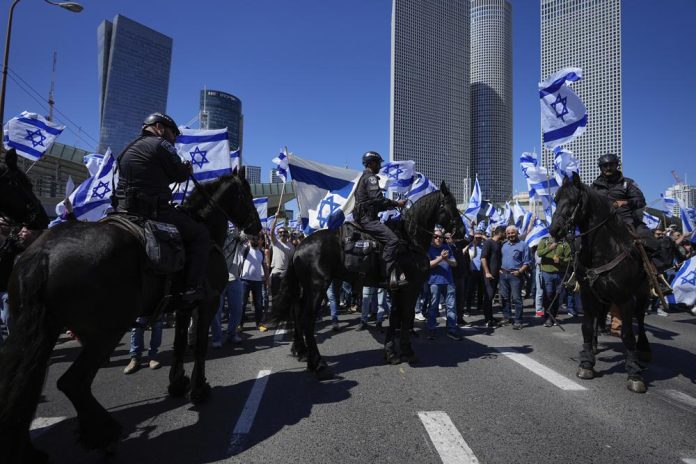Policía montada desplegada ante un grupo de manifestantes israelíes que cortó una calle en protesta por los planes de reforma judicial del gobierno del primer ministro, Benjamin Netanyahu, en Tel Aviv, Israel, el jueves 9 de marzo de 2023. (AP Foto/Ohad Zwigenberg)