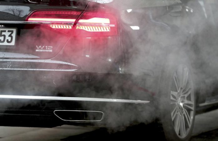 ARCHIVO - Un auto de lujo Audi está rodeado de gases de escape, estacionado con el motor encendido frente a la Cancillería en Berlín, 20 de noviembre de 2019. (AP Foto/Michael Sohn, File)